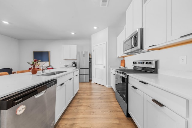 kitchen with sink, light hardwood / wood-style flooring, a breakfast bar, appliances with stainless steel finishes, and white cabinets