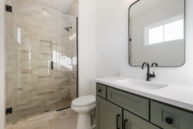 bathroom featuring vanity, a shower with door, and toilet