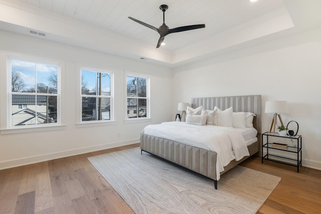 bedroom featuring wood ceiling, ceiling fan, a raised ceiling, and light wood-type flooring