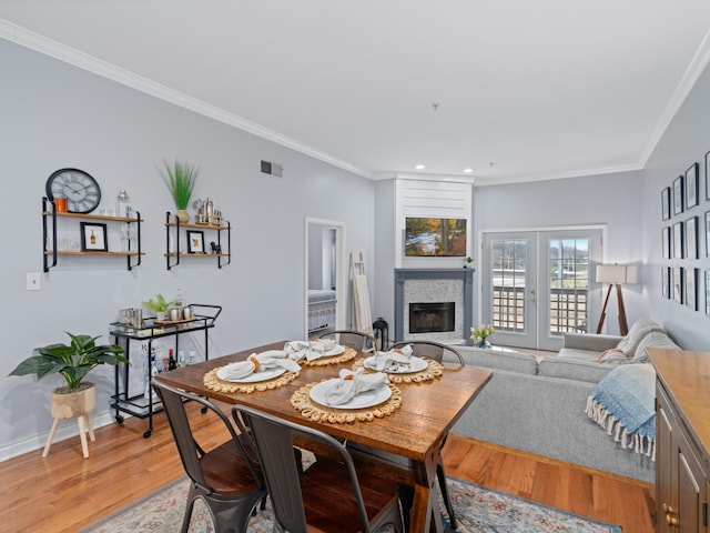 dining room with hardwood / wood-style flooring, ornamental molding, and french doors