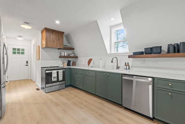 kitchen featuring stainless steel appliances, sink, green cabinets, and light hardwood / wood-style flooring