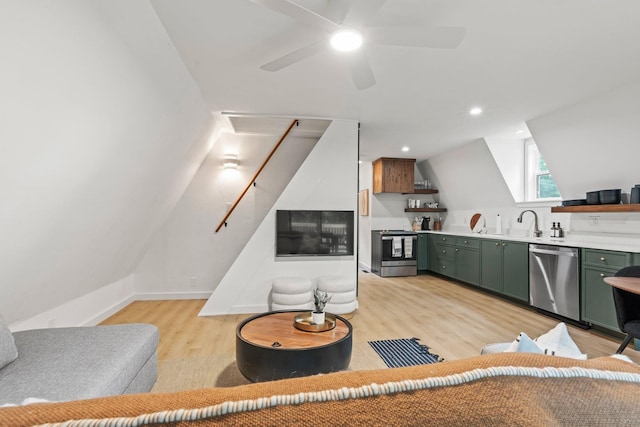 kitchen with lofted ceiling, sink, green cabinetry, light wood-type flooring, and stainless steel appliances