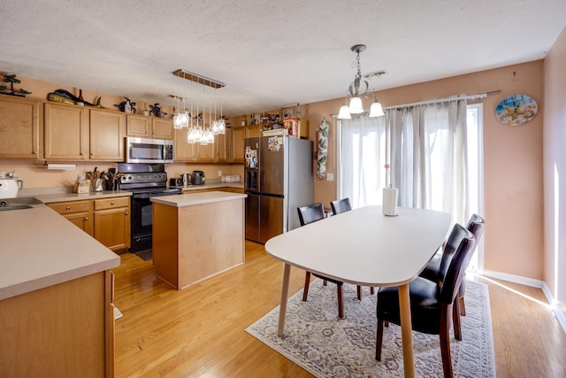 kitchen featuring pendant lighting, stainless steel appliances, light hardwood / wood-style floors, and a kitchen island