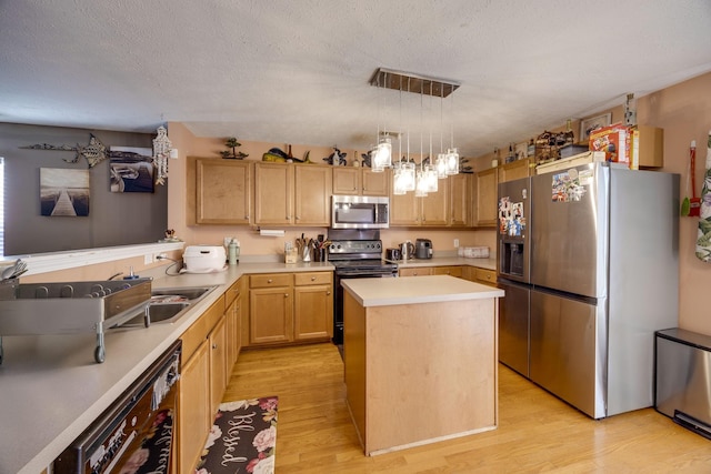 kitchen with light brown cabinetry, hanging light fixtures, a center island, black appliances, and light wood-type flooring