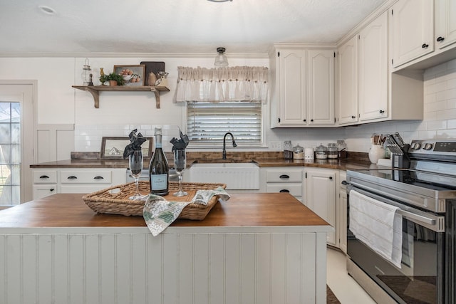 kitchen with white cabinetry, sink, electric range, and a kitchen island