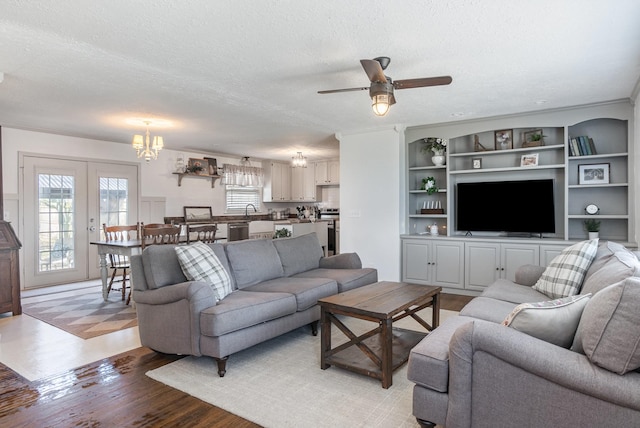 living room featuring ceiling fan with notable chandelier, light hardwood / wood-style flooring, and a textured ceiling