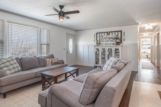 living room featuring crown molding, ceiling fan, light hardwood / wood-style flooring, and a textured ceiling