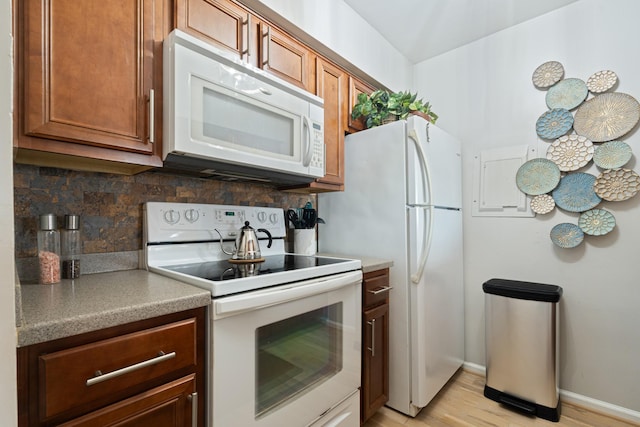 kitchen with tasteful backsplash, white appliances, and light hardwood / wood-style flooring