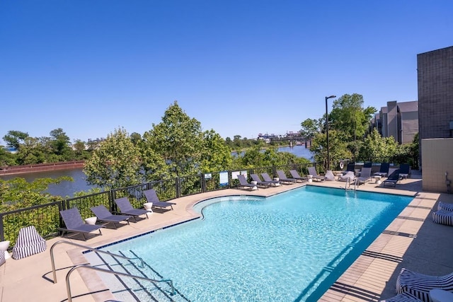 view of swimming pool featuring a patio and a water view