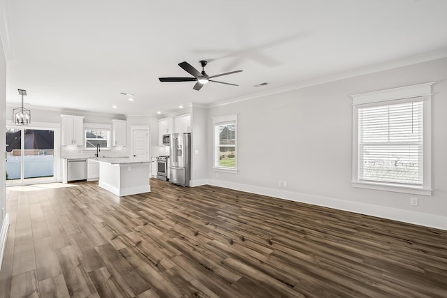 unfurnished living room featuring sink, crown molding, ceiling fan with notable chandelier, and dark hardwood / wood-style floors