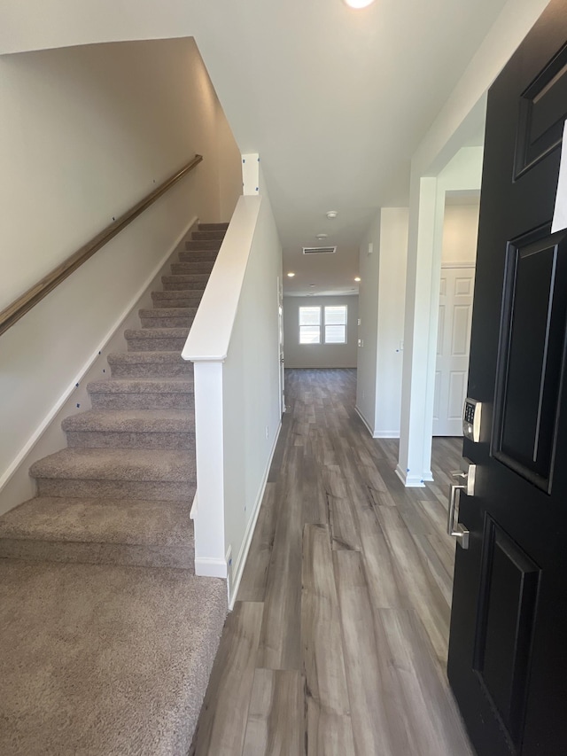 foyer featuring visible vents, stairs, baseboards, and wood finished floors