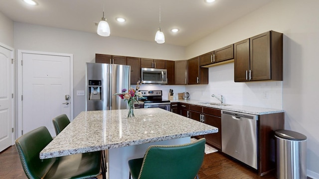 kitchen featuring sink, a breakfast bar, appliances with stainless steel finishes, hanging light fixtures, and a kitchen island