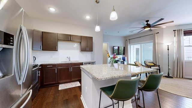 kitchen featuring hanging light fixtures, light stone countertops, appliances with stainless steel finishes, and sink