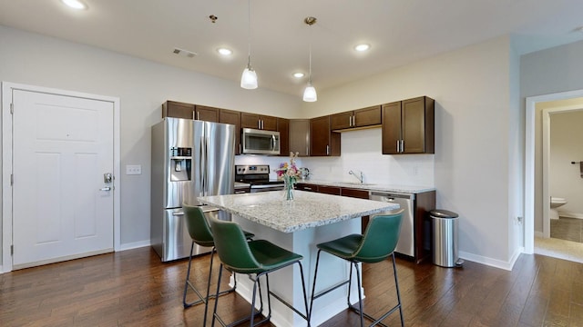 kitchen featuring hanging light fixtures, dark hardwood / wood-style floors, stainless steel appliances, and a center island