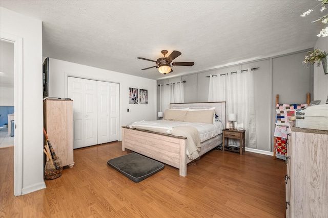 bedroom featuring hardwood / wood-style flooring, ceiling fan, a closet, and a textured ceiling