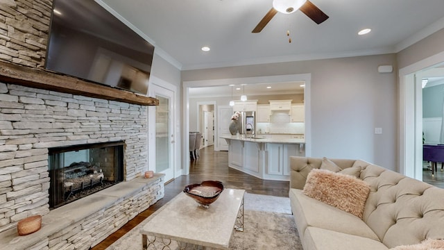 living room featuring crown molding, ceiling fan, wood-type flooring, and a fireplace