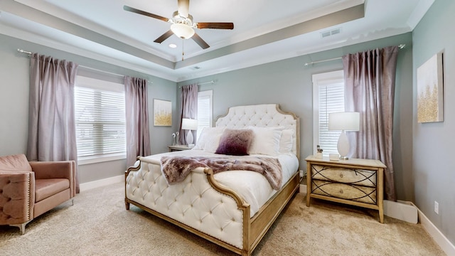 carpeted bedroom featuring a raised ceiling, ornamental molding, and ceiling fan