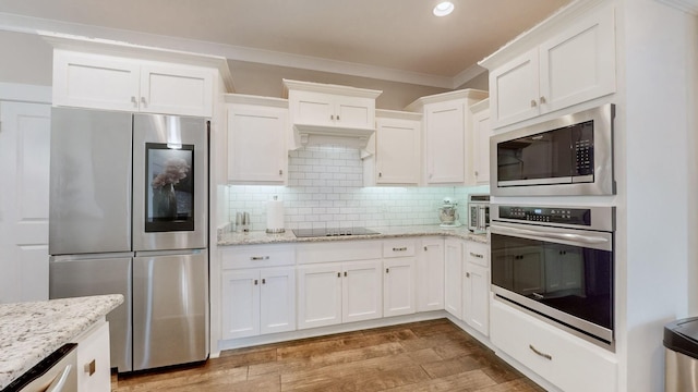 kitchen featuring crown molding, hardwood / wood-style flooring, backsplash, stainless steel appliances, and white cabinets