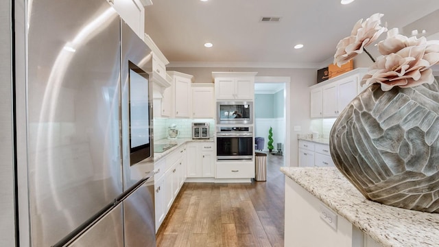 kitchen featuring white cabinetry, light stone counters, ornamental molding, and stainless steel appliances