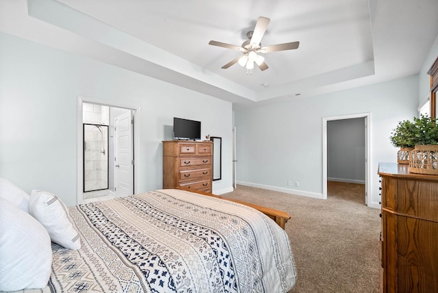 bedroom with ceiling fan, a tray ceiling, carpet, and a spacious closet