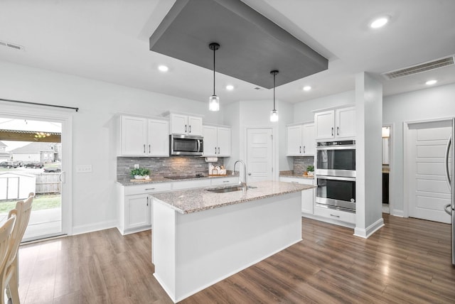 kitchen with white cabinetry, stainless steel appliances, decorative light fixtures, and sink