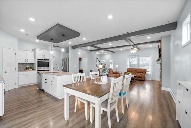 dining area with beamed ceiling, ceiling fan, sink, and dark hardwood / wood-style floors