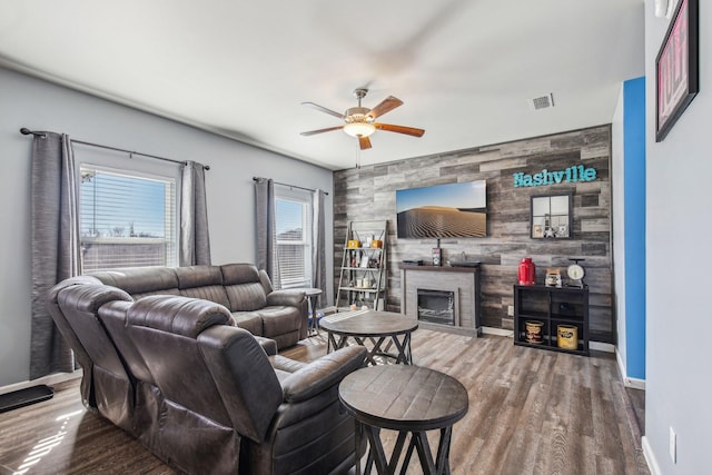 living room featuring ceiling fan, wooden walls, and hardwood / wood-style floors