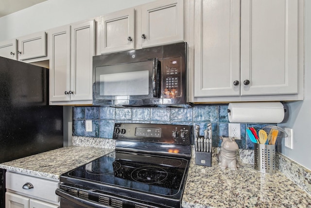 kitchen with light stone counters, decorative backsplash, and black appliances