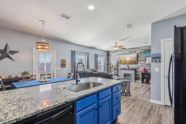 kitchen with sink, blue cabinetry, a fireplace, black appliances, and decorative light fixtures