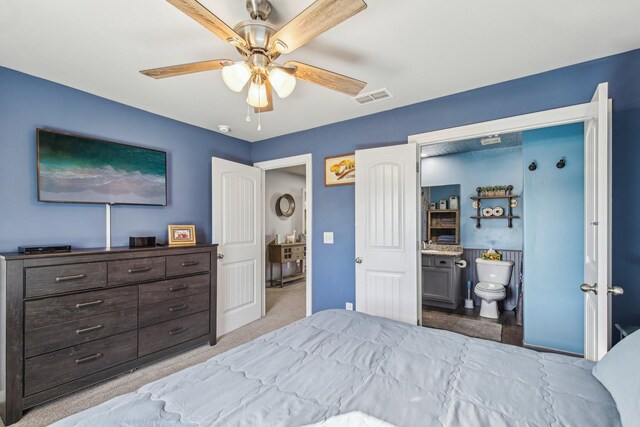 bedroom with light colored carpet, ceiling fan, and ensuite bathroom