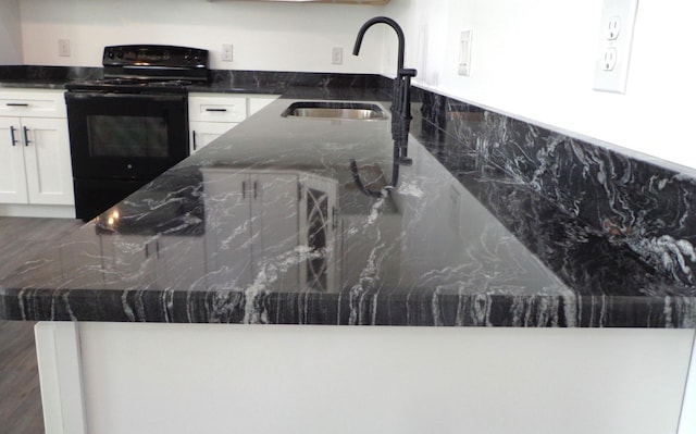 kitchen featuring white cabinetry, dark stone counters, sink, and black range with electric cooktop