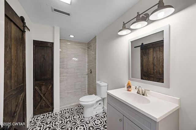 bathroom with vanity, tile patterned floors, toilet, and a tile shower