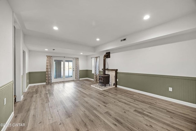 unfurnished living room featuring light hardwood / wood-style floors and a wood stove