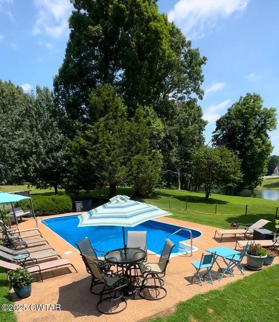 view of swimming pool with a yard, a patio area, and a water view