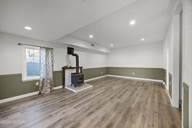 unfurnished living room with light hardwood / wood-style floors and a wood stove