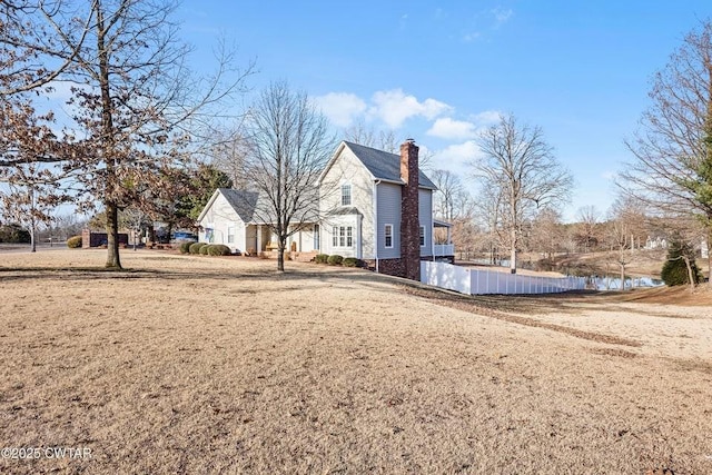 view of home's exterior with a water view and a lawn