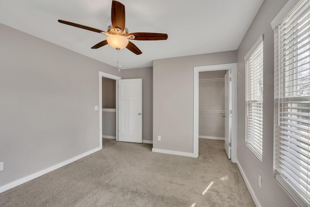 unfurnished bedroom with a walk in closet, light carpet, ceiling fan, and a closet