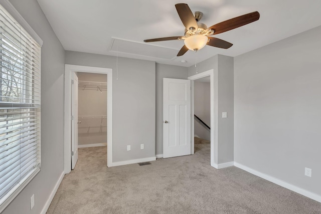 unfurnished bedroom featuring ceiling fan, a spacious closet, a closet, and light carpet