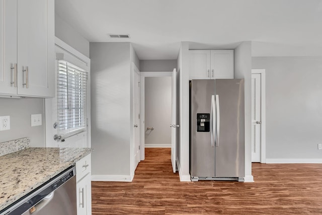 kitchen featuring light stone countertops, white cabinetry, appliances with stainless steel finishes, and dark hardwood / wood-style floors