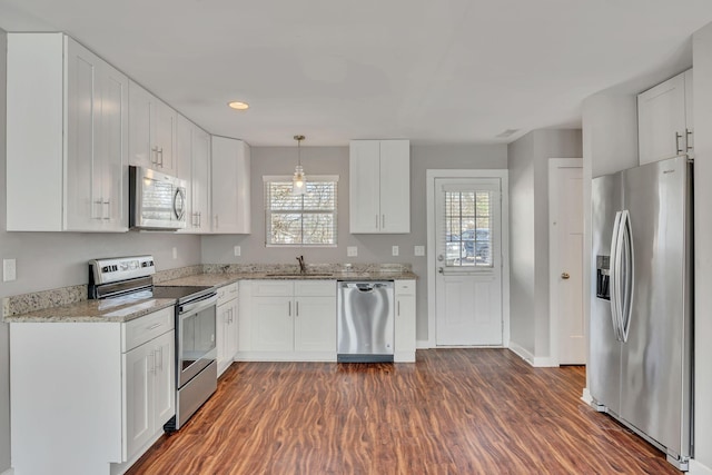 kitchen featuring white cabinetry, stainless steel appliances, dark hardwood / wood-style floors, and hanging light fixtures