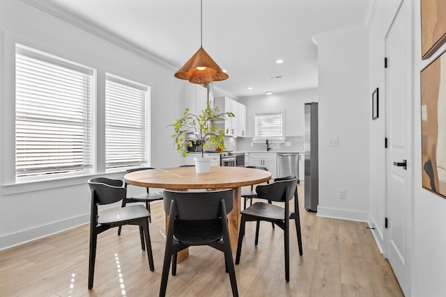 dining room featuring crown molding, sink, and light hardwood / wood-style flooring