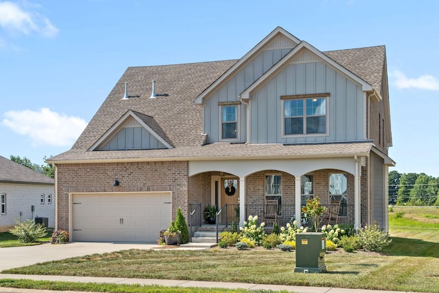 view of front of home with a garage, central AC, a front yard, and covered porch