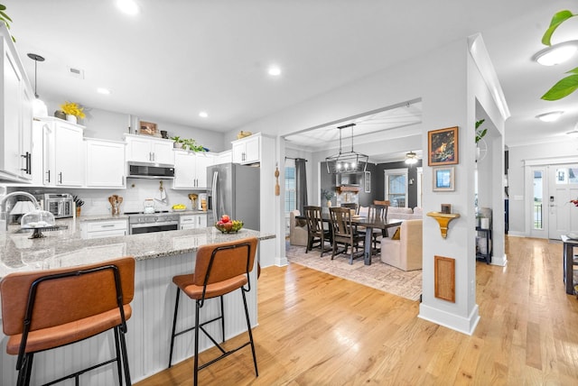 kitchen featuring sink, white cabinetry, tasteful backsplash, stainless steel appliances, and light hardwood / wood-style floors