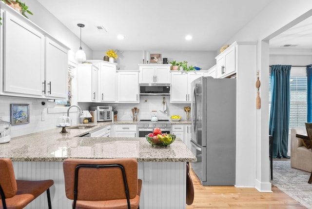 kitchen featuring sink, decorative light fixtures, kitchen peninsula, and appliances with stainless steel finishes