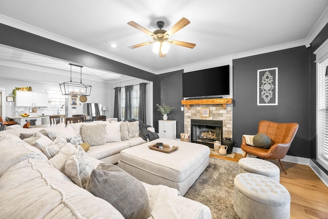 living room featuring ornamental molding, ceiling fan with notable chandelier, and light hardwood / wood-style floors