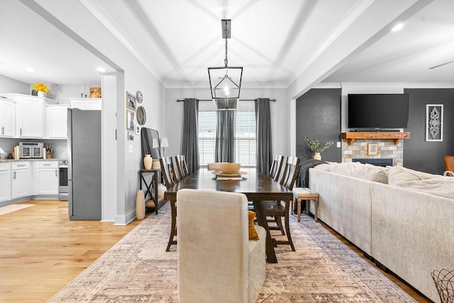 dining area with ornamental molding, a notable chandelier, and light hardwood / wood-style floors