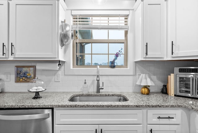 kitchen with white cabinetry, dishwasher, sink, and light stone countertops