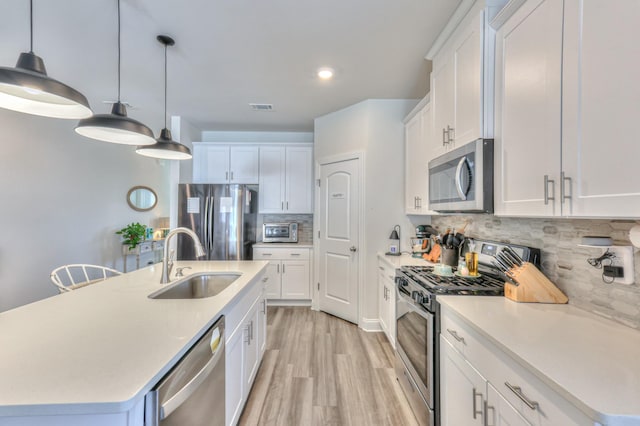 kitchen featuring white cabinetry, appliances with stainless steel finishes, sink, and a center island with sink