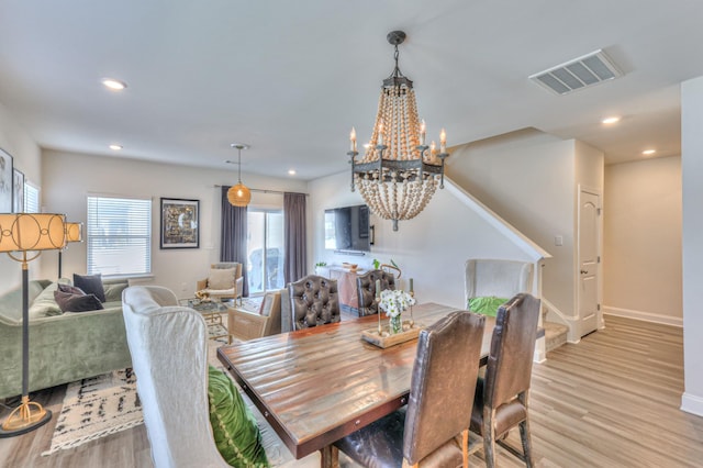 dining area with an inviting chandelier and light hardwood / wood-style floors