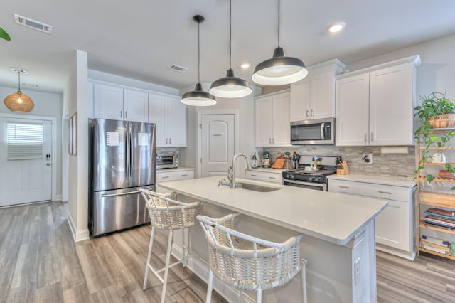 kitchen featuring white cabinetry, appliances with stainless steel finishes, sink, and a breakfast bar area